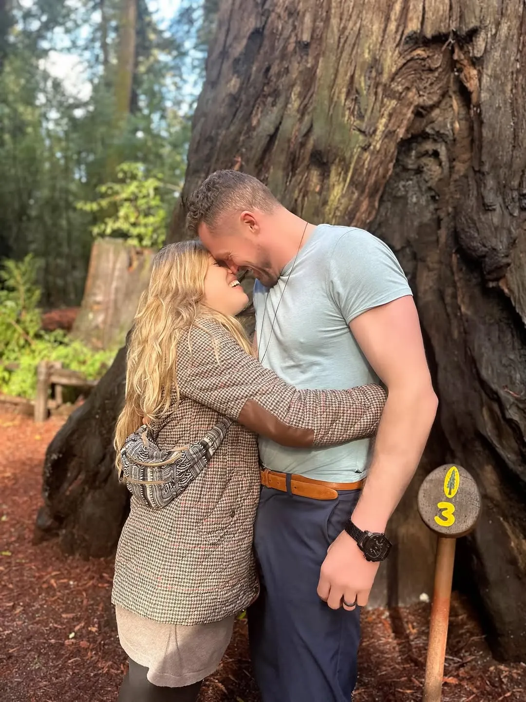 Kyle and Leah embracing at the base of a redwood tree